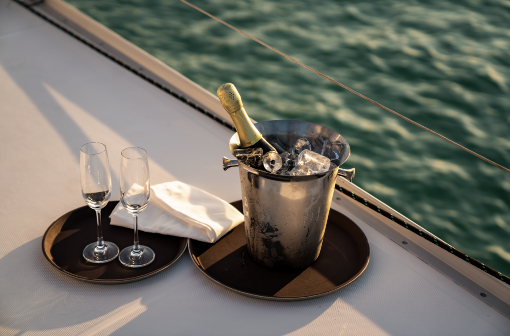 a bottle of champagne sits in a bucket of ice next to two glasses on a yacht