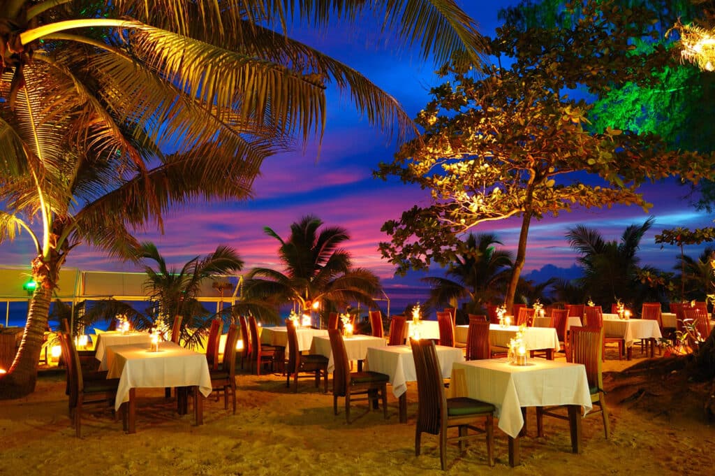 Tables and chairs on a beach with a sunset in the background